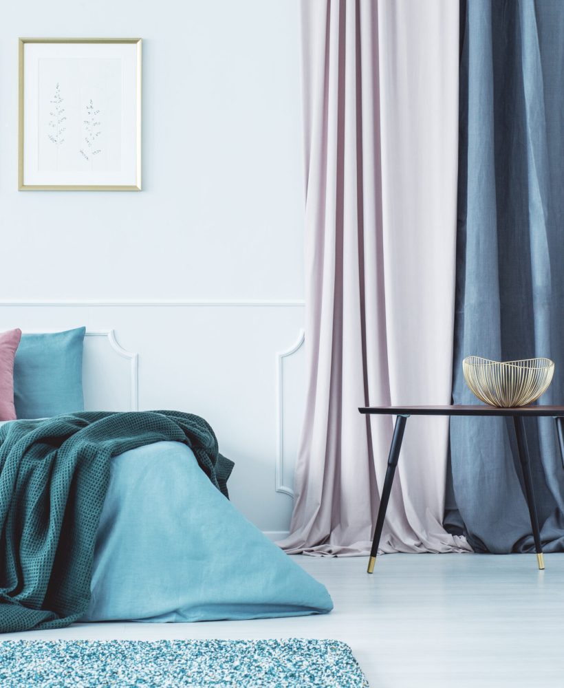 Two posters above bed Two simple posters in gold frames hanging on the wall above double bed standing in bright interior with drapes
